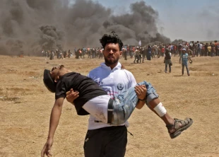 مرد معترض فلسطيني، افرادي را كه توسط رژيم صهيونيستي مجروح شده‌اند، با خود حمل مي‌كند و دنبال راه نجاتي براي آنها مي‌گردد.