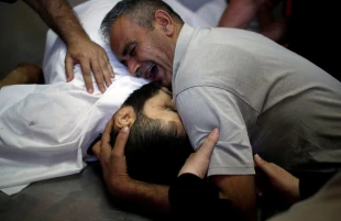 مرد فلسطيني كه برادر مبارز خود را در جريان اعتراضات از دست داده است، پيكر بي‌جان او را در آغوش كشيده و مي‌گريد.